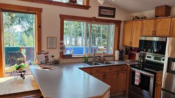 A kitchen with wooden cabinets, a stainless steel refrigerator, and a large window.