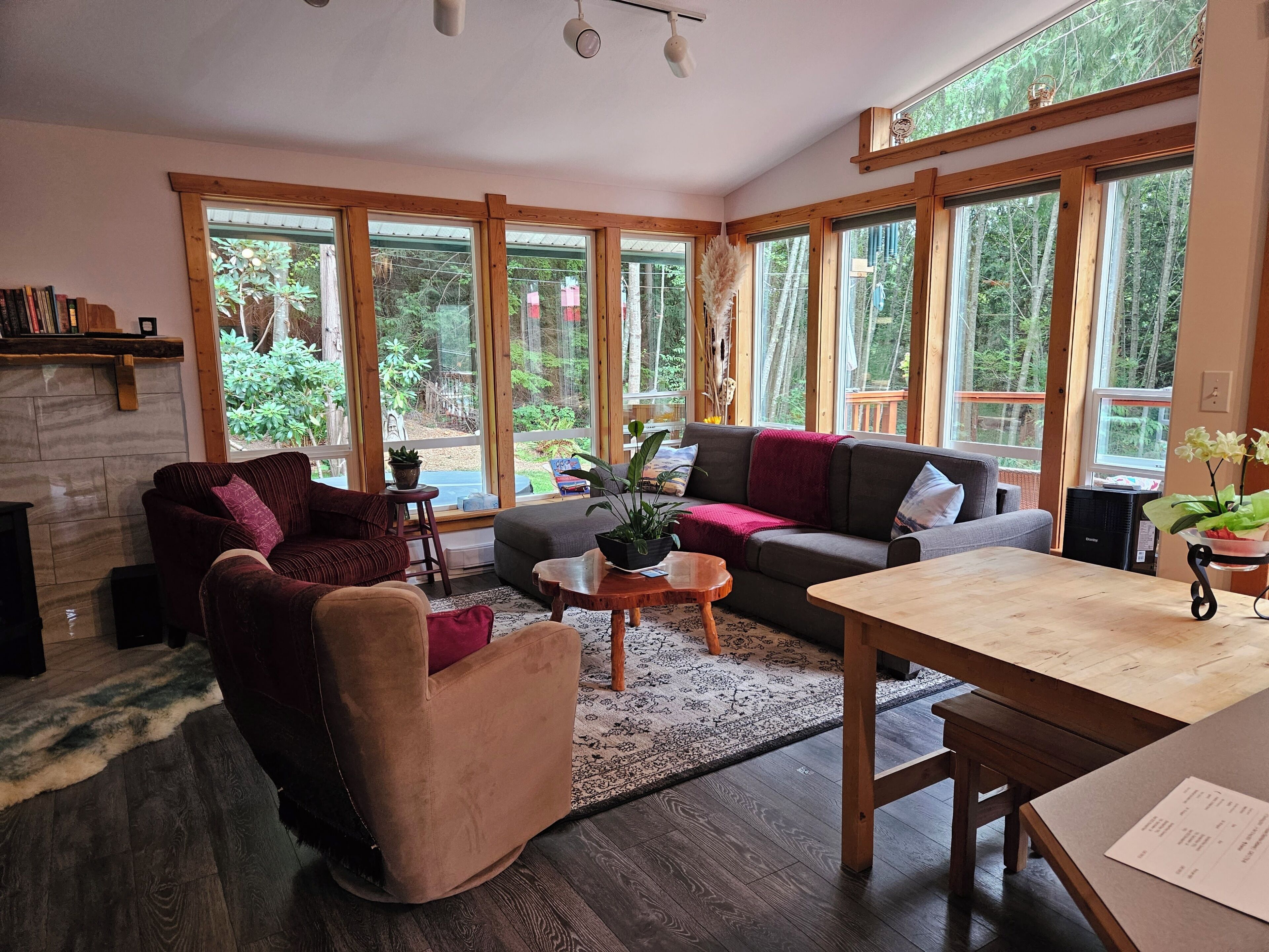 Un salon chaleureux avec une cheminée, de grandes fenêtres et une table en bois.