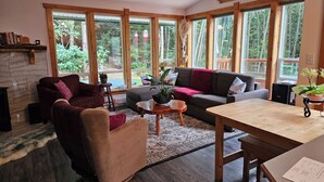 Een gezellige woonkamer met een open haard, grote ramen en een houten tafel.