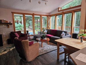 Un salon chaleureux avec une cheminée, de grandes fenêtres et une table en bois.