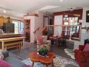 Un salon chaleureux avec une table à manger en bois, un canapé, un fauteuil rouge et une petite table basse en bois sur laquelle est posée une plante.