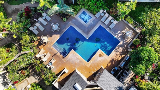 Vue aérienne d’un hôtel doté d’une piscine centrale, de plusieurs espaces de détente et d’une végétation luxuriante.