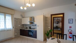 Eine moderne Küche mit Einbauofen, ein Essbereich mit Tisch und Stühlen sowie ein Wohnzimmer mit Sofa und Kamin.
