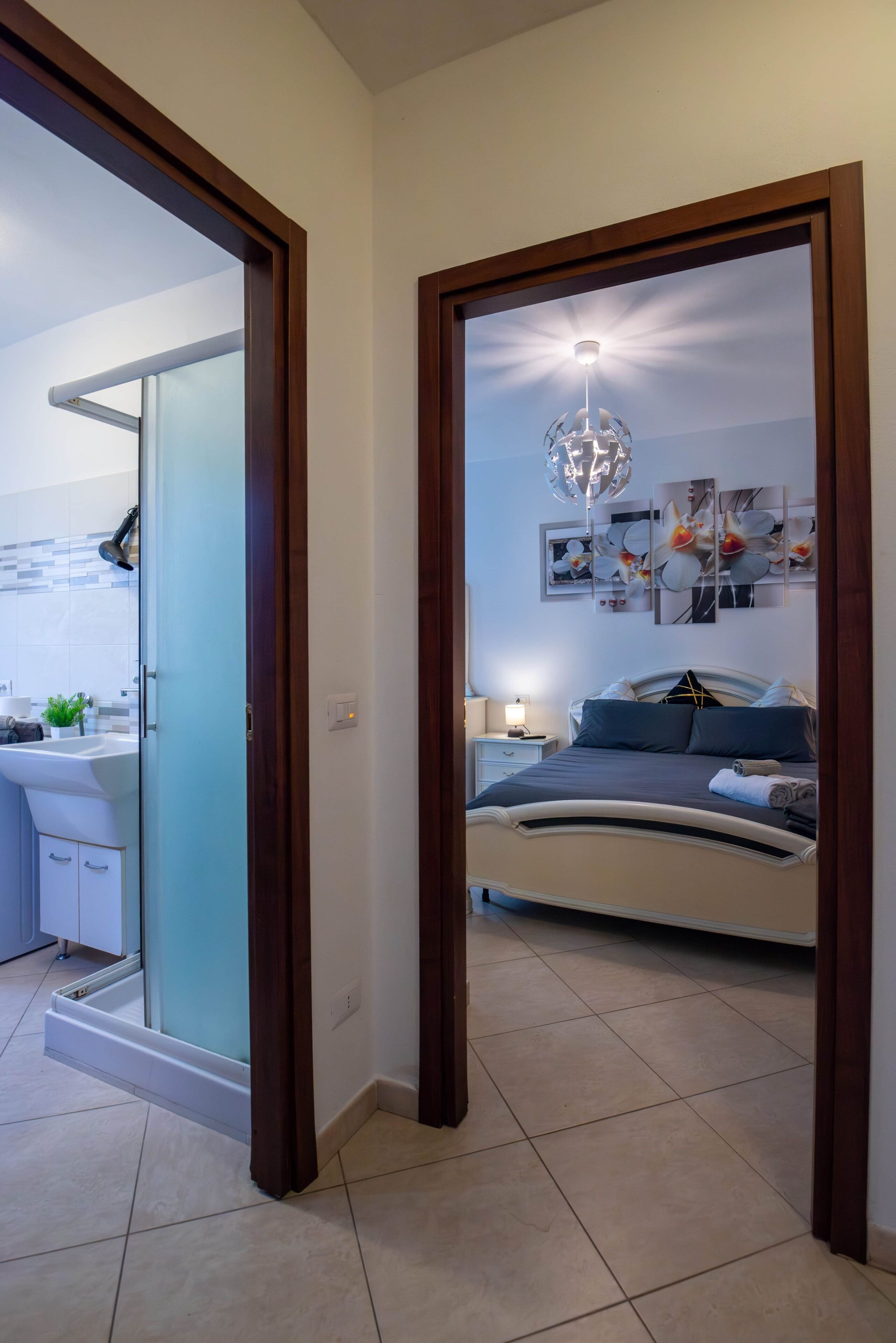 A bedroom with a bed, a bedside table, a wall-mounted light fixture, and a ceiling fan.