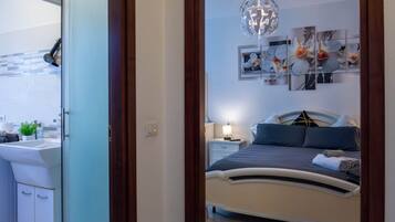 A bedroom with a bed, a bedside table, a wall-mounted light fixture, and a ceiling fan.