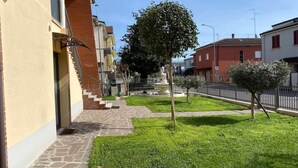 Ein Innenhof mit einem Brunnen, einem Baum und einer Treppe, die zu einem Gebäude führt.