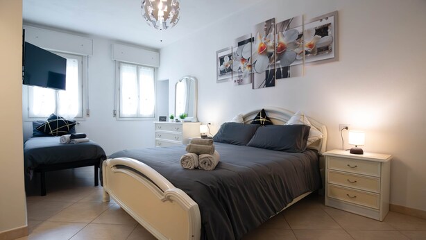 Ein Schlafzimmer mit einem Bett, Nachttischen, einer Kommode, einem Spiegel und Bildern an der Wand.