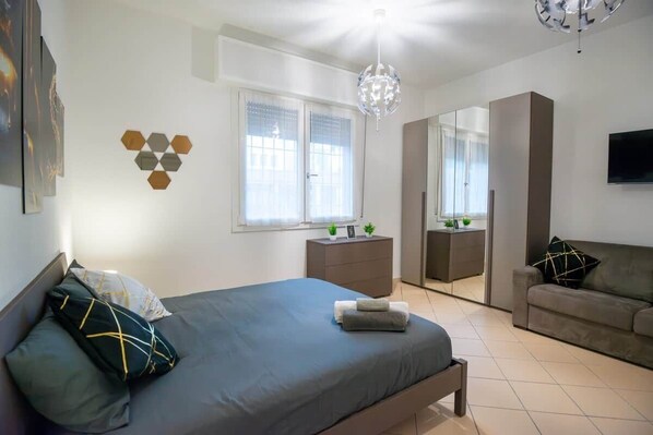A modern bedroom with a bed, dresser, and a mirror.