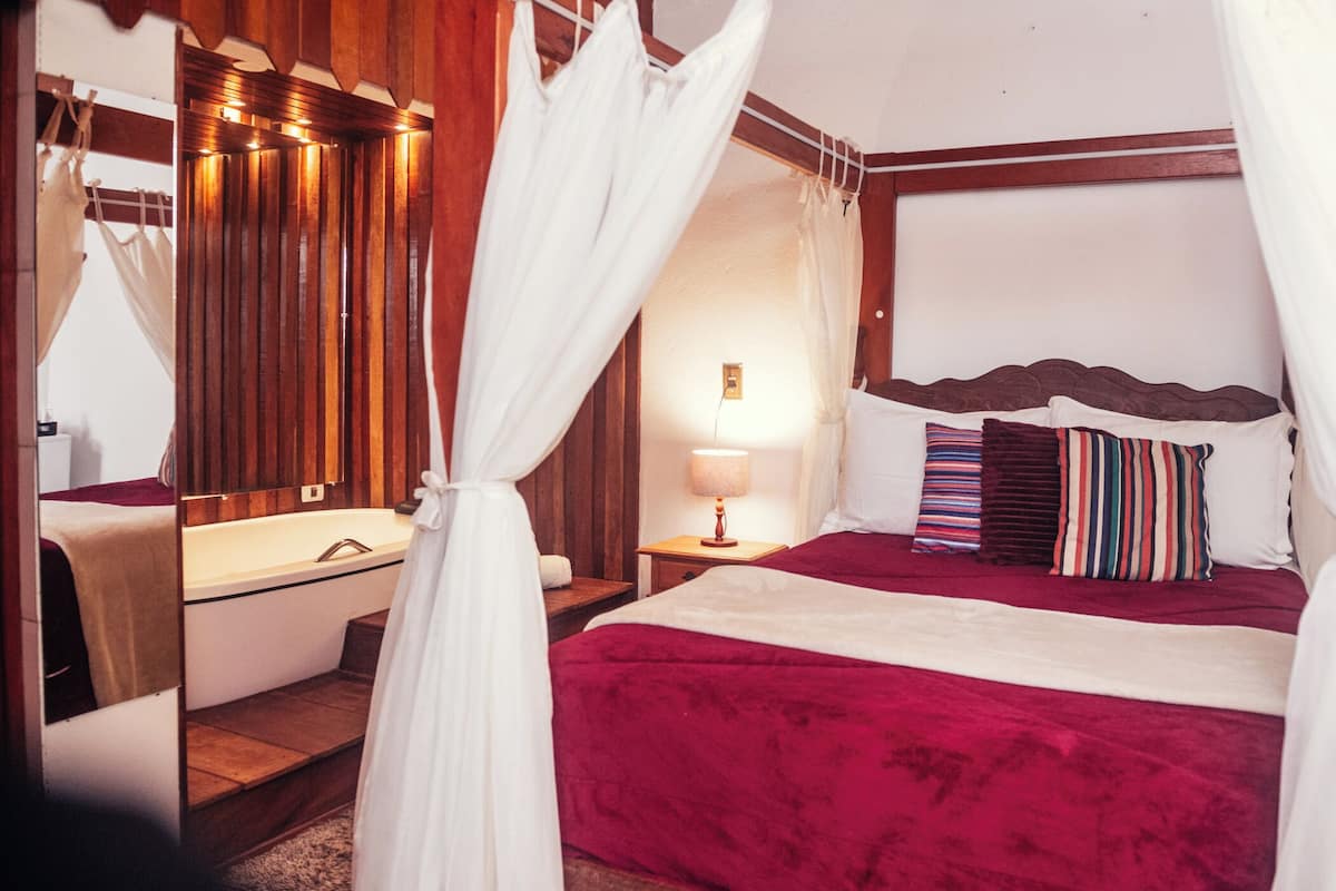 Ein Schlafzimmer mit einem Himmelsbett, einem Nachttisch mit Lampe und einem Holzkopfteil.