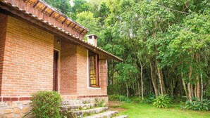 Um edifício de tijolos com varanda, rodeado por vegetação exuberante.