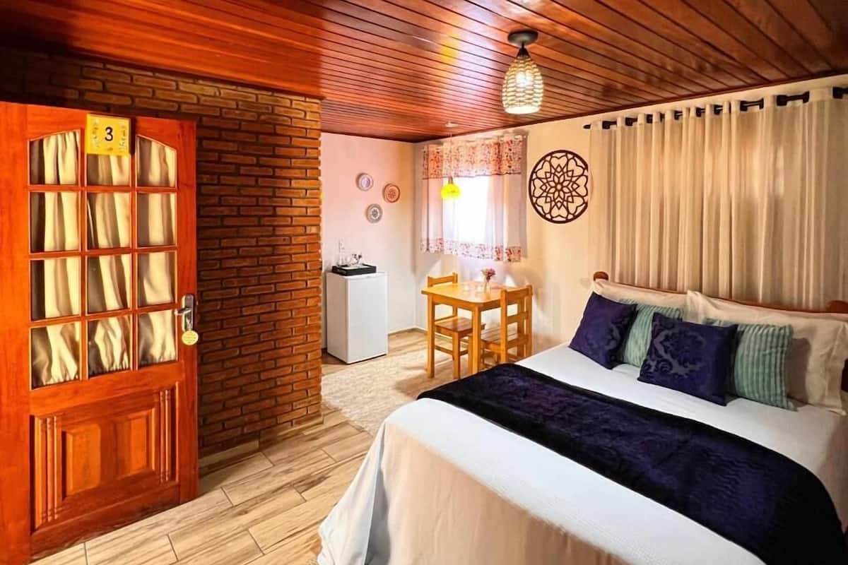 Ein Schlafzimmer mit Bett, Schreibtisch, Stuhl, kleinem Kühlschrank und einer Tür mit einer Nummer.