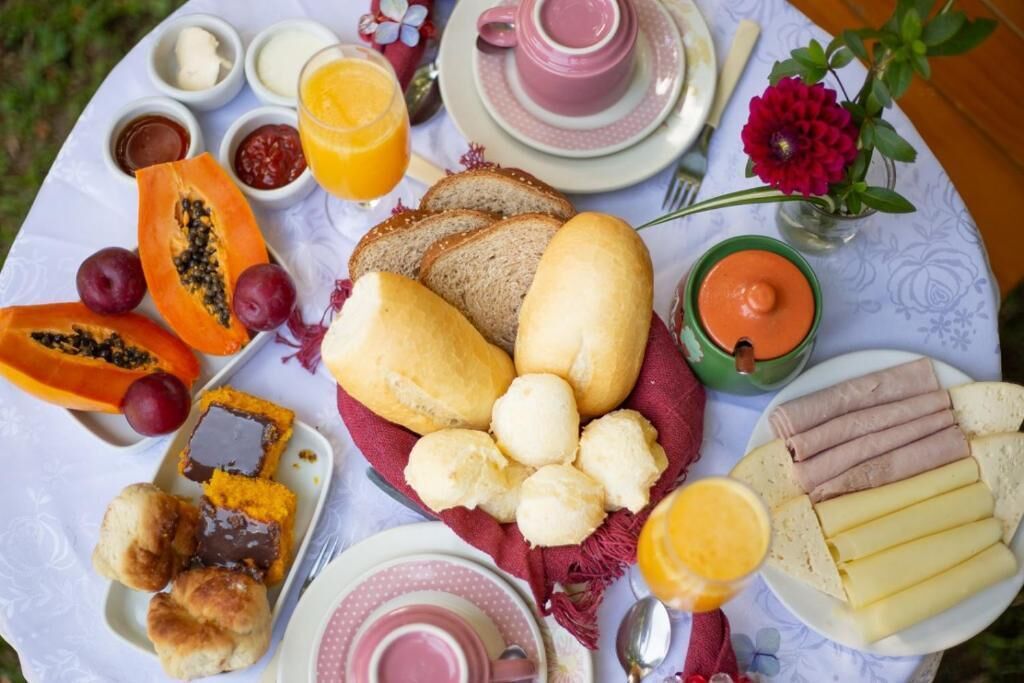 Uma mesa com pão, doces, frutas e acompanhamentos para um piquenique.