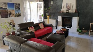 Ein Wohnzimmer mit Kamin, einer Couch, einem Couchtisch und einer Zimmerpflanze.