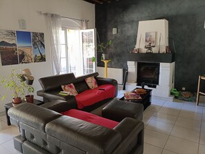 A living room with a fireplace, a sofa, a coffee table, and a potted plant. - Small manor house (Saint-Médard-en-Jalles)