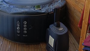 Ein Whirlpool mit Bedienfeld, einem Dampfgenerator und einer Holzwand mit einem Gemälde.