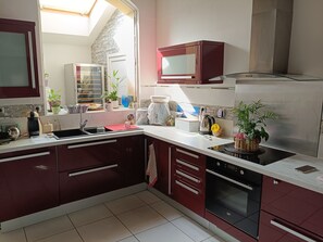 A modern kitchen with a built-in oven, a microwave, and a stainless steel range hood. - Small manor house (Saint-Médard-en-Jalles)
