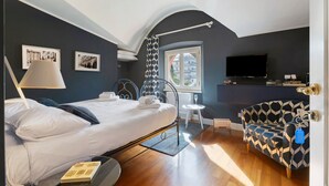 A bedroom with a bed, a chair, a TV, and a window with a view. - 1890 – Deluxe Room – Whirlpool Bath – Wi-Fi – Air Conditioning (Chiavari)