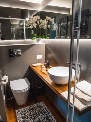 Une salle de bain moderne avec un grand miroir, un lavabo blanc et un espace douche.