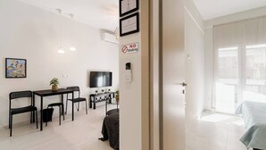 Een modern appartement met een eethoek, een televisie, een 'Niet roken'-bord en een balkon met een bed.