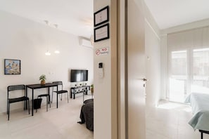Eine moderne Wohnung mit Essbereich, Fernseher, einem Rauchverbot-Schild und einem Balkon mit einem Bett.