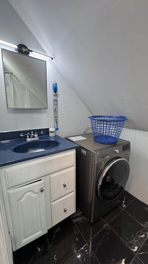 Ein kleines Badezimmer mit Waschbecken, Spiegel und Waschmaschine.