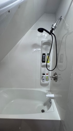 Eine Badewanne mit Duschbrause, Seifenspender und einer Shampoo-Flasche.