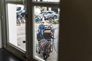 A view through a window of a street scene with a cart, bicycles, and parked cars. - Amazing scenic city view room The Lake Suites (Brugge)