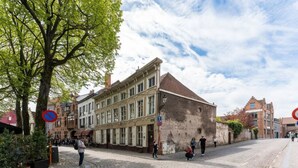 A cobblestone street with historic buildings, a no parking sign, and pedestrians. - Amazing scenic city view room The Lake Suites (Brugge)
