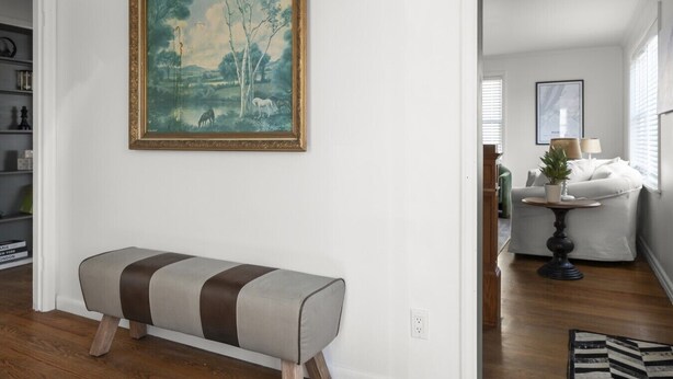 Un salon comprenant un banc, un tableau, un canapé, une lampe et une petite table sur laquelle est posée une plante.