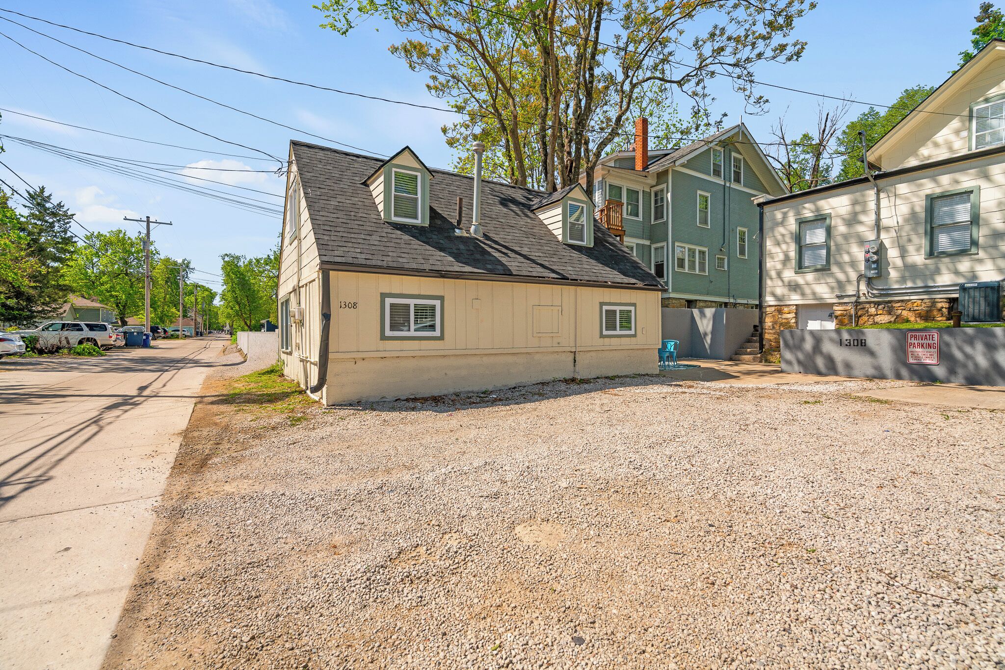 A residential area with houses, a gravel driveway, and a private parking sign.