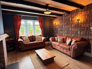 A cozy living room with two leather sofas, a wooden coffee table, and a bookshelf filled with books. - Spacious Family Getaway Hot Tub, Sauna & Garden (Conwy Principal Area)