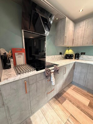 A modern kitchen with grey cabinetry, a black stove, and a coffee maker. - Spacious Family Getaway Hot Tub, Sauna & Garden (Conwy Principal Area)
