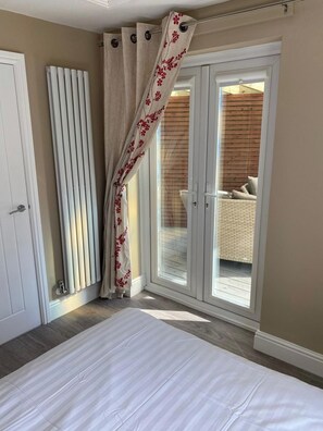 A bedroom with a bed, a sliding glass door leading to a balcony, and a radiator. - Spacious Family Getaway Hot Tub, Sauna & Garden (Conwy Principal Area)