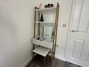 A white door with a silver handle, a white wall, and a white shelf unit with a mirror and storage compartments. - Carmen Sylva Llandudno Beach Family  Flat (Llandudno)