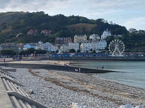 A coastal town with a promenade, a large Ferris wheel, and buildings with varied architecture. - Carmen Sylva Llandudno Beach Family  Flat (Llandudno)