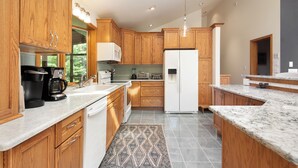 A modern kitchen with wooden cabinets, a white refrigerator, and a marble countertop. - Hudson Valley Private Retreat with 3 bedrooms, 2 living spaces, and a pond. (Hillsdale)