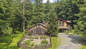 A rustic wooden cabin with a fenced garden, surrounded by dense forest. - Hudson Valley Private Retreat with 3 bedrooms, 2 living spaces, and a pond. (Hillsdale)