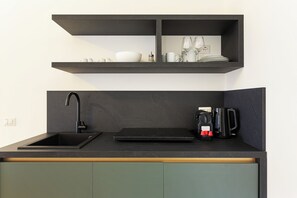 A kitchen with a black countertop, a black sink, and a coffee maker. - Pharmacy B (stresa)