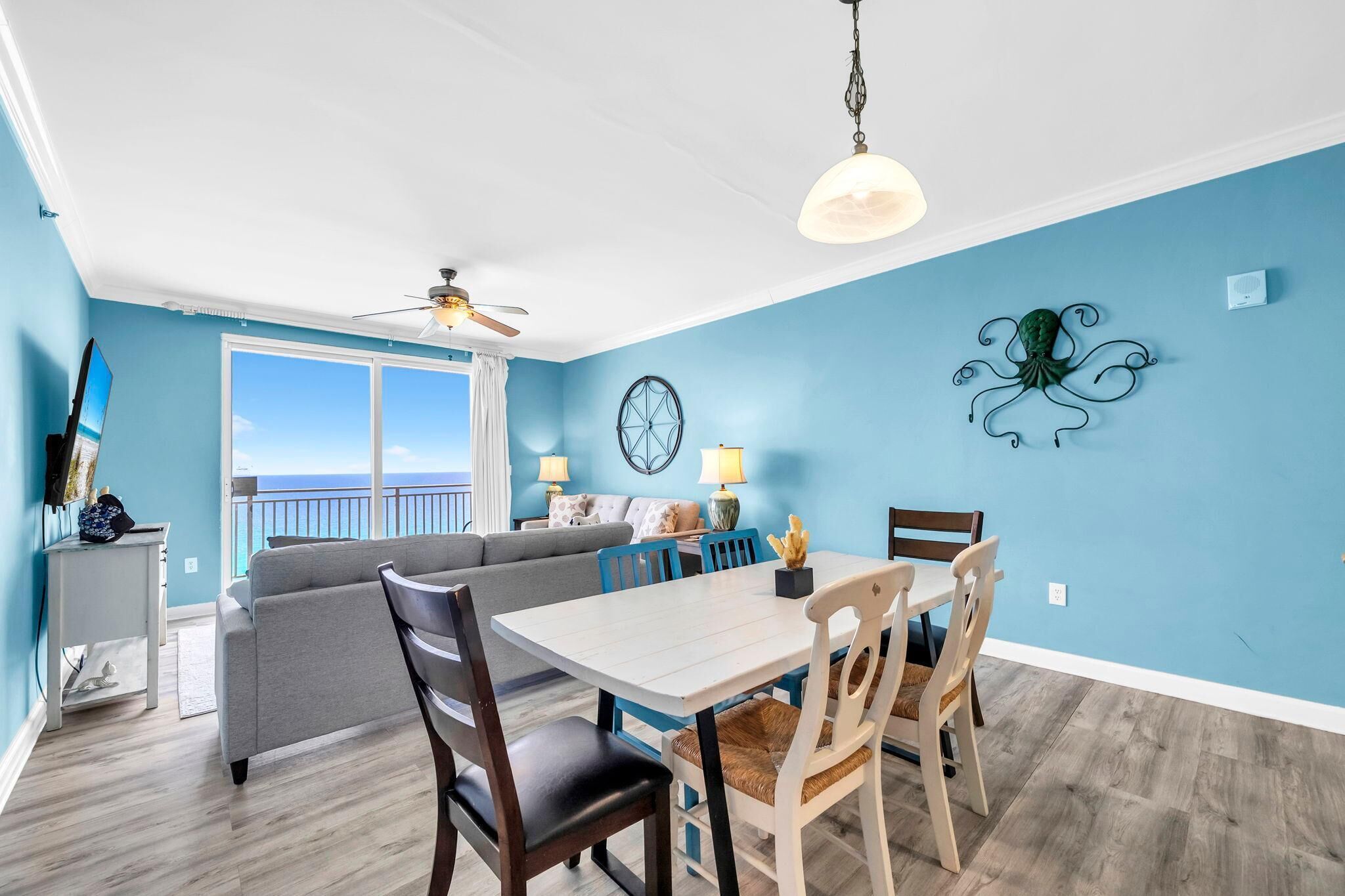 Un salon comprenant un canapé, une table à manger, des chaises, un ventilateur de plafond et donnant sur l’extérieur.
