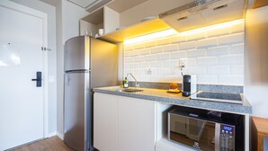 Eine kompakte Küche mit integriertem Mikrowellenherd, einem Edelstahlkühlschrank und einer Arbeitsfläche mit Spüle.