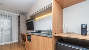 Eine moderne Küche mit Holzschränken, einem eingebauten Backofen, einer Mikrowelle und einem schwarzen Kühlschrank.