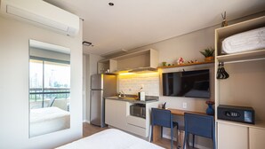 Ein kompaktes Hotelzimmer mit einer Küchenzeile, einem Bett, einer Essecke und Blick auf die Stadt.