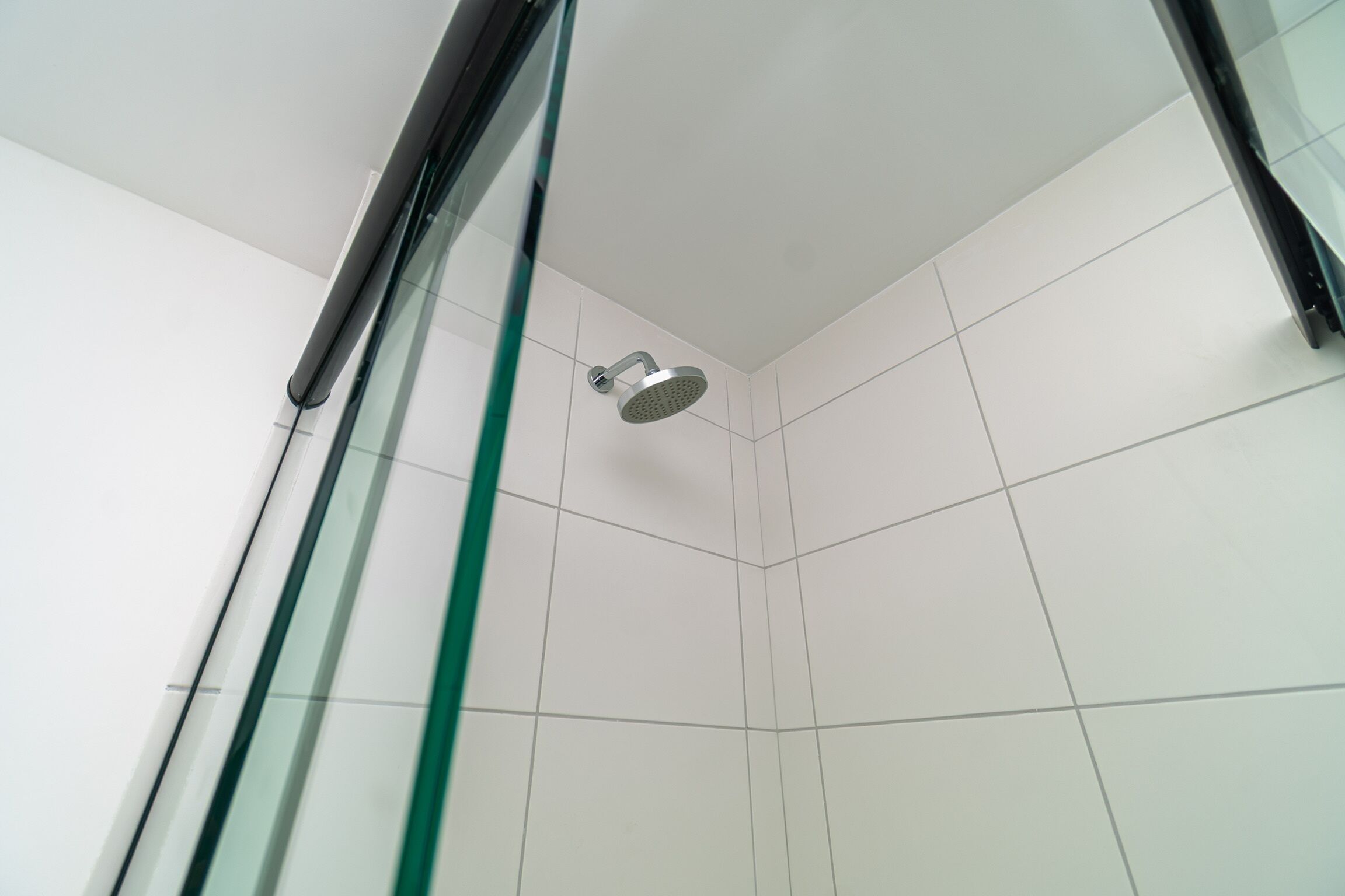 Una doccia con porta in vetro e soffione flessibile.