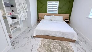 A bedroom with a bed, a wardrobe, a nightstand, a window, and a patterned rug.