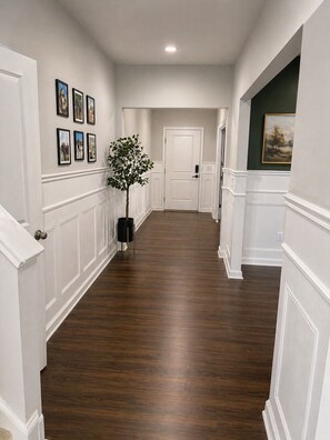 A hallway with white wainscoting, a potted plant, and framed pictures on the wall. - Spacious 5-bedroom house in lovely Castle Hayne, minutes to wrightsville beach (Castle Hayne)
