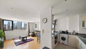 A modern apartment with a city view, a living area with a sofa and coffee table, a kitchen with a washing machine, and a dining area. - East India Dock Road, London (Greater London)