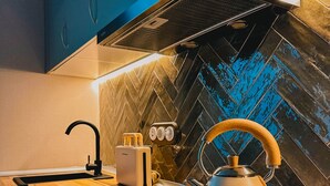 Eine moderne Küche mit Fischgrätenmuster-Fliesen an der Spritzschutzeinrichtung, einem Wasserkocher, einem Toaster und einem eleganten schwarzen Induktionskochfeld.