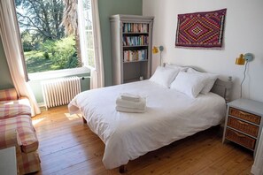 Une chambre à coucher avec un lit, une bibliothèque, une fenêtre donnant sur un beau paysage et une décoration murale.