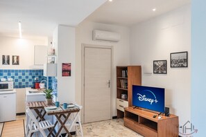 A compact living space with a kitchenette, a dining area, a TV, and a bookshelf. - [Heart of Genova A] De Ferrari 3 min • A/C • WiFi (Genova)