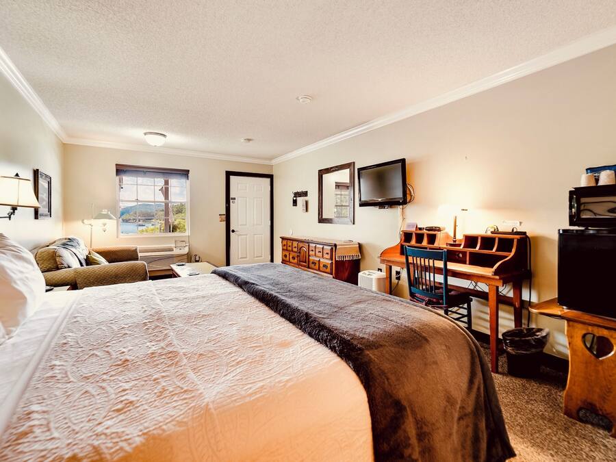 A hotel room with a bed, a desk, a chair, a television, and a window with a view.